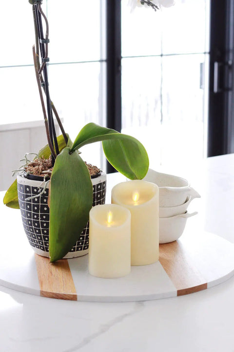 Ivory Scalloped Edge Flameless LED Pillar Candle With Real Wax Look Moving Flame No Mess, next to green plant