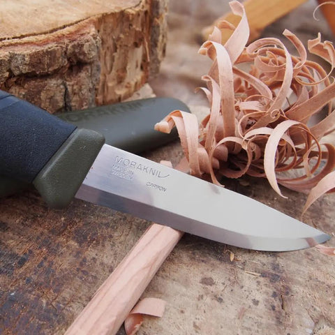 Companion Carbon Steel Fixed Blade Knife With Sheath 4.1 Inch Blade Military Green shown carving wood shavings