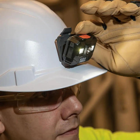 Rechargeable LED Headlamp for Hard Hats, 300 Lumen Work Light, mounted on a hard hat, shown being adjusted by a gloved hand.