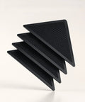 Four black triangle heavy duty rug gripper pads with adhesive strips, showing textured surface. Heavy Duty Rug Gripper Pads With Adhesive Strips For Non Slip Carpet Corners Kit Includes Four Pads And Four Auxiliary Stickers Edge Guard And Extra Grip For Home Or Office.