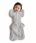 Baby in gray cotton Swaddle Up Sleep Sack For Newborns, Arms Up Self Soothing Swaddle, Improves Sleep And Calms Startle Reflex