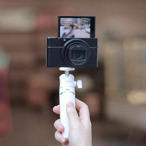 Person holding MT-08 White Mini Tripod For Camera With 1 Quarter Inch Mount 2 In 1 Extendable Handheld Video Stand