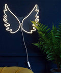 Cloud Neon LED Wall Light Sign USB Powered Night Lamp for Home with angel wing design on a wall by a plant