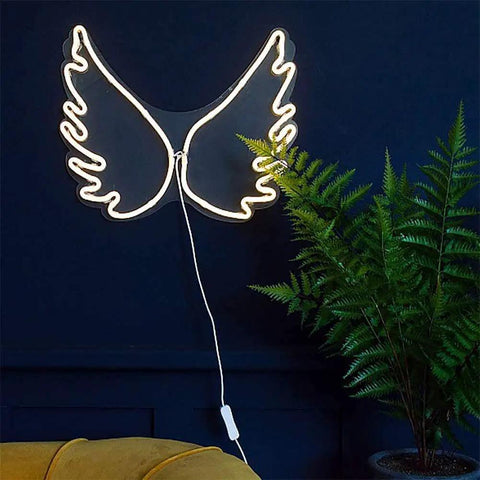 Cloud Neon LED Wall Light Sign USB Powered Night Lamp for Home with angel wing design on a wall by a plant