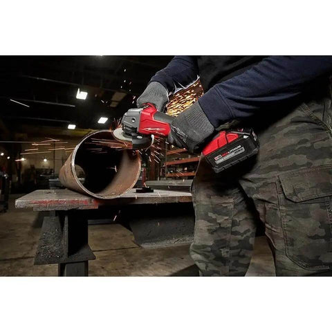 User operating Badass M18 Brushless Angle Grinder Kit 4-1/2 Inch 5-Inch on metal pipe with sparks flying.