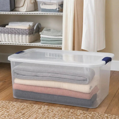 66 Quart Clear Plastic Storage Bin With Secure Blue Latch Lids Stackable Home Organization Tote For Garage Closet And Pantry with folded blankets inside.