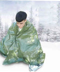 Person wrapped in olive green 3 Pack Thermal Survival Blankets Emergency Kit For Beach Mat Camping Rug Tent Ground Cover Reflective Foil Gear