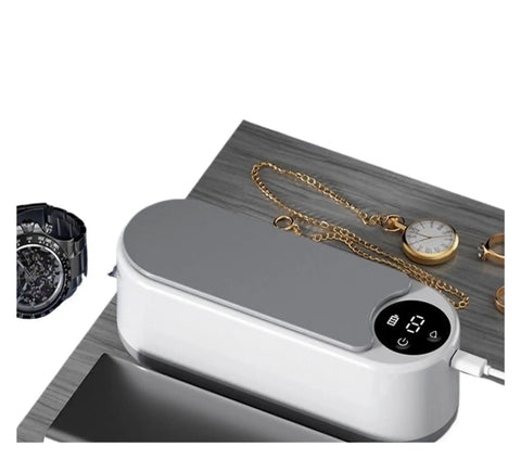 Totally Slick Portable Ultrasonic Cleaner For Sparkling Jewelry And Flawless Eyeglasses Hella Efficient Rechargeable Cleaning Pod on wooden surface with jewelry and watch.