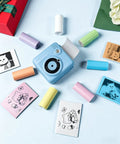 12 Pack BPA Free Instant Print Paper Refills For Kids Cameras, High Quality Thermal Paper Rolls With Glossy Finish, Non Sticky Tear Resistant And Jam Free, Easy Load For Crisp Clear Photo Prints Every Time. Blue kids camera with colorful thermal paper rolls and printed photos