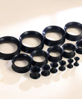 Dope Black Silicone Ear Gauges Set With 15 Pairs And 24 Pieces Stretching Kit For Ear Tunnels From 2G To 25mm displayed on table.