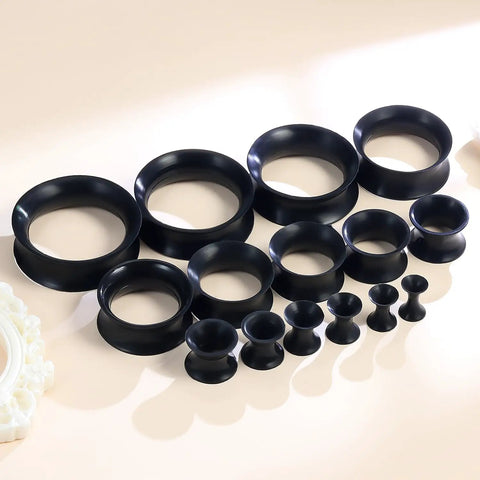 Dope Black Silicone Ear Gauges Set With 15 Pairs And 24 Pieces Stretching Kit For Ear Tunnels From 2G To 25mm displayed on table.