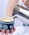 20 Oz Milk Frothing Pitcher Stainless Steel 304 Durable Espresso Steaming Jug pouring milk into a latte for art creation