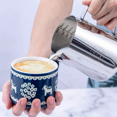 20 Oz Milk Frothing Pitcher Stainless Steel 304 Durable Espresso Steaming Jug pouring milk into a latte for art creation