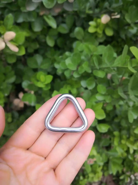 Hand holding Beefy Stainless Steel 316 Marine Grade Triangle Ring Buckle Welded V Shaped Heavy Duty Ring against greenery
