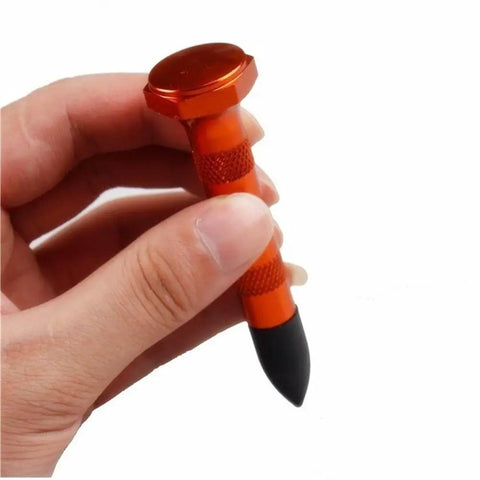 Close-up of DIY Paintless Dent Repair Kit part, an orange tap down pen with plastic tip held in hand for small dings and hail damage.