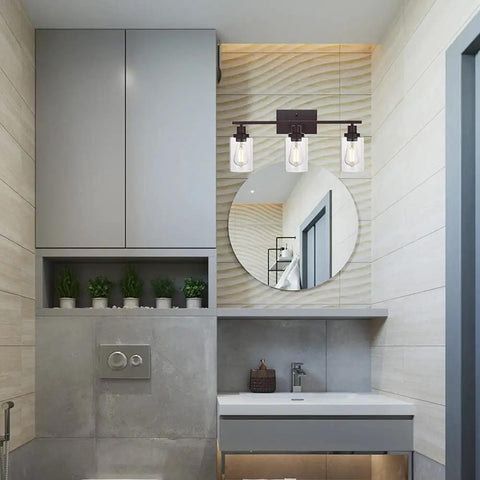 Bathroom with Three Light Vanity Light In Oil Rubbed Bronze, Industrial Wall Sconce With Clear Glass Shades Above Round Mirror