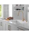 Modern Single Handle Kitchen Sink Faucet With Pull Down Spray Head And Built In Soap Dispenser, Magnetic Self Docking, Brushed Gold Finish in stylish kitchen setting.