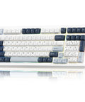 Game Ready Mechanical Keyboard Featuring Slick Tri Mode Wireless Bluetooth And 2.4GHz Setup For Lag Free Multi Device Pairing And A Rock Solid USB C Wired Backup For Gamers, compact design with white and navy keycaps.