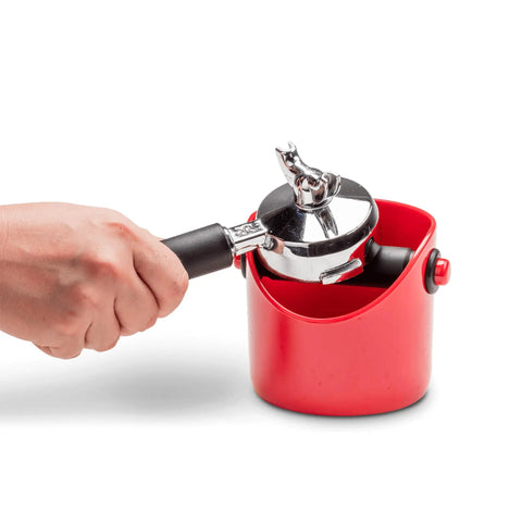 Hand dumping espresso grounds into Grindenstein Espresso Knock Box Sturdy Compact Space Saving Kitchen Sidekick Red Durable Rubber Sleeve