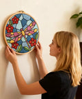 Woman hanging Dragonfly Punch Needle Kit For Adults Beginners Colorful Flower Embroidery Starter Set with hoop on wall.