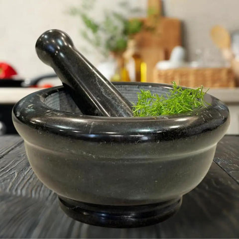 Heavy Duty Granite Mortar And Pestle Set 6 Inch Stone Grinder For Fresh Guacamole Salsa And Pesto Crush Herbs And Spices With Ease Non Slip Base Durable Black Kitchen Essential with herbs visible inside.