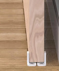 Side view of installed 4 Pack POM Plastic T Shape Adjustable Sliding Barn Door Floor Guides With Screws White Finish on wooden floor