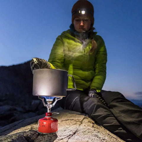 Person using Ultralight Folding Camping Stove That Fits In Your Pocket, Boils 1 Liter In About 3.5 Minutes on a rocky surface.