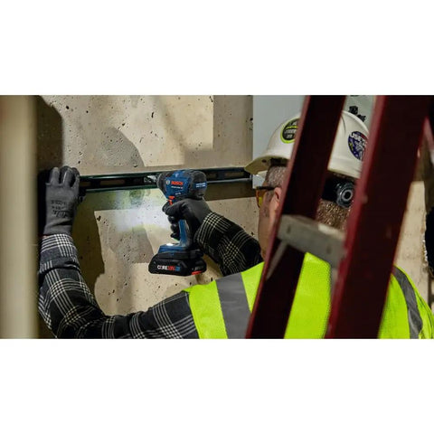 Worker using 18V Brushless Connected-Ready 1/4 In Hex Impact Driver Bare Tool With Auto Bolt Release on construction site wall.