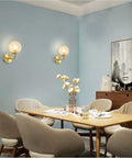 Lit Water Ripple Lampshade Double Gold Wall Sconce Set in dining room setting, lighting up a modern space with antique brass finish.