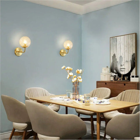 Lit Water Ripple Lampshade Double Gold Wall Sconce Set in dining room setting, lighting up a modern space with antique brass finish.
