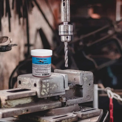 Close-up of a drill press with Boss Grade Synthetic Lubricant Paste For MQL Metalworking Industrial Pink Hard Paste Multi Use 4 Oz jar nearby.