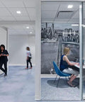 Modern office with glass wall, woman working in a cubicle, white walls equipped with White Vinyl Wall Base Self-Stick Ultra Thick 1/8 Inch, 4.25 Inch By 80 Feet Peel And Stick Adhesive Backing, Flexible Floor Base Trim For Walls And Baseboards, Toe-Friendly Easy Install, Durable, Easy To Clean