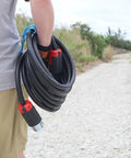 Person carrying Real Deal 150 Foot Spider Box Generator Extension Cord Featuring 50 Amp Twist Lock Outlets on a gravel path.
