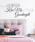 Bedroom with Always Kiss Me Goodnight black quote peel and stick wall decal above a grey upholstered headboard.