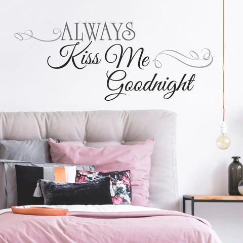Bedroom with Always Kiss Me Goodnight black quote peel and stick wall decal above a grey upholstered headboard.