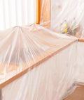 20 Pack Heavy Duty Pro Grade Plastic Drop Cloths 9x12 Feet For Painting covering furniture in a room for protection.