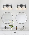 Three Light Black Vanity Light Fixture Over Mirror With Clear Glass Shades For Sleek Modern Bathroom E26 Bulb Compatible Industrial Farmhouse Style Wall Lighting mounted above dual mirrors on white wall.