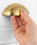 Hand holding Brushed Gold Cabinet Pull with 3 Inch Hole Centers Bin Cup Handles Pack Of 10 Zinc Alloy for cabinets and drawers.