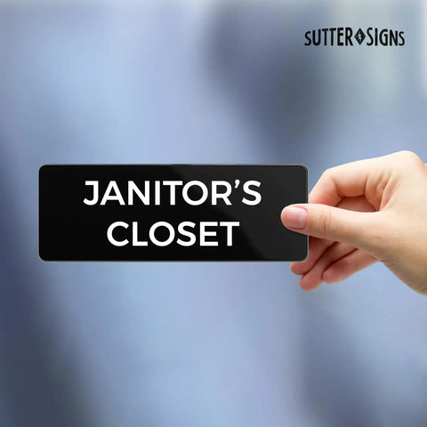 Hand holding a Durable ABS Door Sign With Full Adhesive Backing 2x6 Inch, No Tools Needed Mount On Door Or Wall, High Visibility Label For Janitor Closet