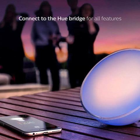 Go White And Color Portable Dimmable LED Smart Light Table Lamp on wooden table at sunset with smartphone nearby