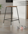 Oval Silicone Chair Leg Caps For Irregular Furniture Legs on black stool on tile floor with extra caps visible