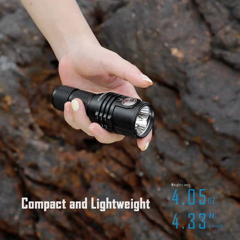 Hand holding Ultra Bright EDC Flashlight 13000 Lumens, Rechargeable Pocket Light For Camping And Hiking, Emergency Prep, USB C Recharge, Compact 4.5 Inch Size, Long Lasting Battery against rocky background