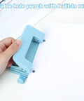 Person using a blue Two Hole Paper Punch Metal Blue Desktop Puncher For File Folders And Loose Leaf Books Beefy Built To Last Heavy Duty