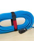 All Purpose Cable Straps 18 Inch By 1 Inch 2 Pack Black For Cable Management At Office Data Center Home Or Truck Quick Wrap Reusable Hook And Loop Tie Downs securing blue cable on table.