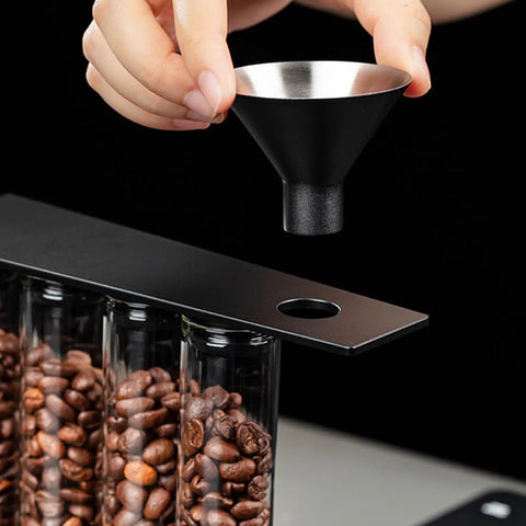 Glass Coffee Bean Storage Tubes Set Of Six With One Way Degassing Valve And Magnetic Stand And Single Dose Espresso Dosing Vials being filled with coffee using a funnel.