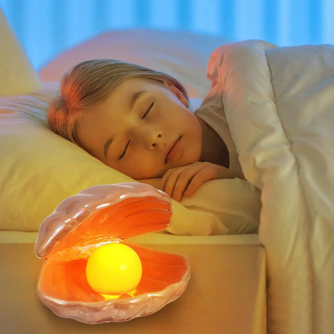 Seashell LED Mood Lamp, Portable Pearl Night Light beside sleeping child, emitting cozy glow, ceramic seashell on nightstand.