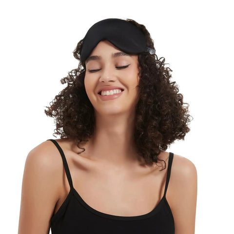 Silk Sleep Mask With Contoured Foam Padding For Light Blocking And No Pressure on woman's forehead, smiling with eyes closed.