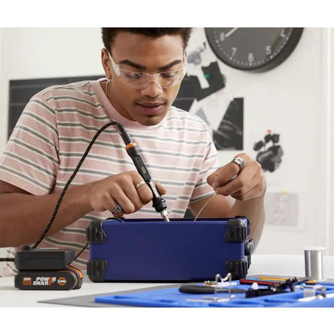 Young man using Top Tier Cordless Pen Engraver And Digital Soldering Iron Kit With Sweet 20V Battery and Solid 46 Piece Wood Burner for DIY.