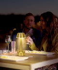 Cordless Gold Battery Operated Table Lamp For Dining Ambience on outdoor table with two people dining at night