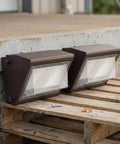 CONGARTENO Outdoor Security Flood Light 2 Pack Dusk to Photocell Wall Mount placed on a wooden pallet with a screw nearby.